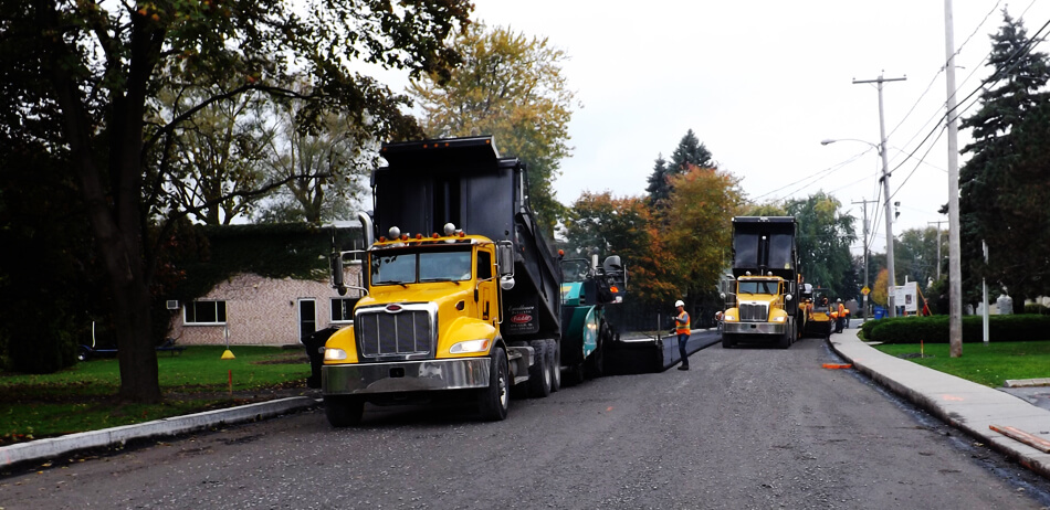 Vue lointaine sur deux camions de chargement d'asphalte